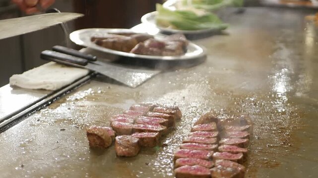 POV to kobe sirloin wagyu steak while cooking on teppan yaki flat pan in japanese style restaurant for lunch time. Chef cooking wagyu kobe beef sirloin steak on teppanyaki flat pan