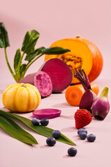 Vibrant Still Life of Fresh Fruits and Vegetables on Pastel Backdrop, Pumpkin, blueberries, carrots, beetrootcots, banana, celery on a pink background