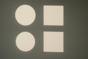 Geometric light projection creates captivating visual display on wall, featuring two circles and two squares. interplay of shapes and shadows evokes sense of simplicity and elegance