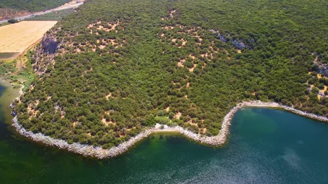 Drone footage captures the breathtaking aerial perspective of Bafa Lake, a tranquil natural wonder in Turkey. The video showcases the lake's calm turquoise waters contrasting with the vibrant green