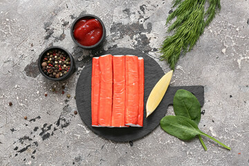 Black board with tasty crab sticks and different spices on grey background © Pixel-Shot