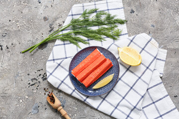 Plate with tasty crab sticks, cut lemon and dill on grey background © Pixel-Shot