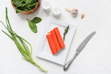 Plate with tasty crab sticks, spinach leaves and green onion on white background © Pixel-Shot