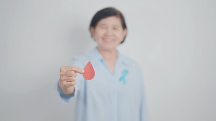Elderly woman with Blue ribbon and red Blood drop for World Diabetes Day, Blue November Health, Prostate Cancer awareness, Blood sugar check, Insulin, Glucose screening, donation and Health checkup