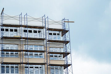 Construction site of residential building with scaffolding and windows.