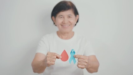 Elderly woman with Blue ribbon and red Blood drop for World Diabetes Day, Blue November Health, Prostate Cancer awareness, Blood sugar check, Insulin, Glucose screening, donation and Health checkup