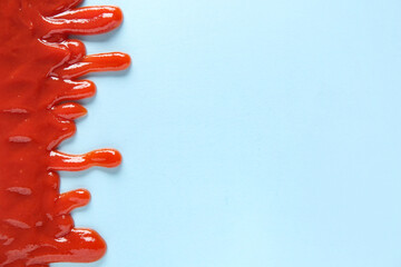 Spilled tasty ketchup on blue background