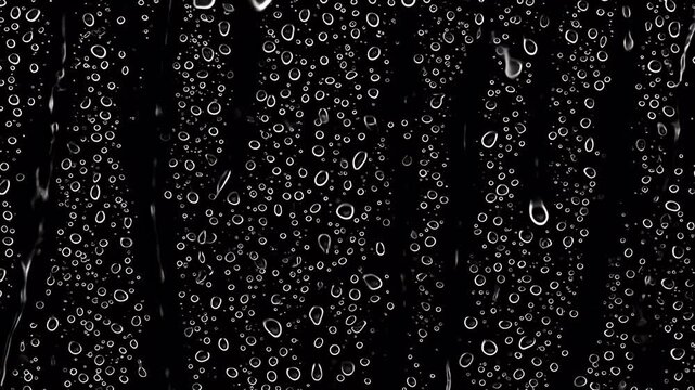 Close up of water droplets on a black surface.