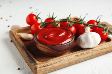 Wooden tray with bowl of tasty ketchup and ingredients on white grunge background, closeup