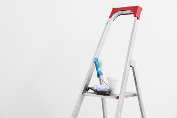 Maintenance ladder with paint roller near white wall