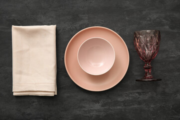 Plate with bowl, glass and napkin on black grunge background