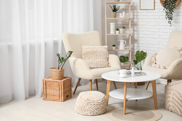 Table and white soft armchairs in interior of living room