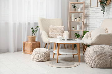 Table and white soft armchairs in interior of living room
