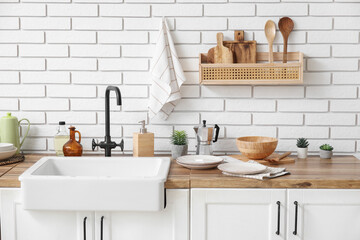 Clean napkins and different dishware on counters near white brick wall in kitchen