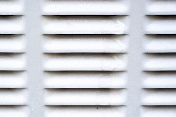 Close-up of a white vent grid with horizontal slats. The abstract pattern and neutral color make...