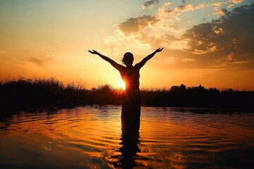 Silhouette of a person standing in water with arms raised at sunset surrounded by calm nature and dramatic sky