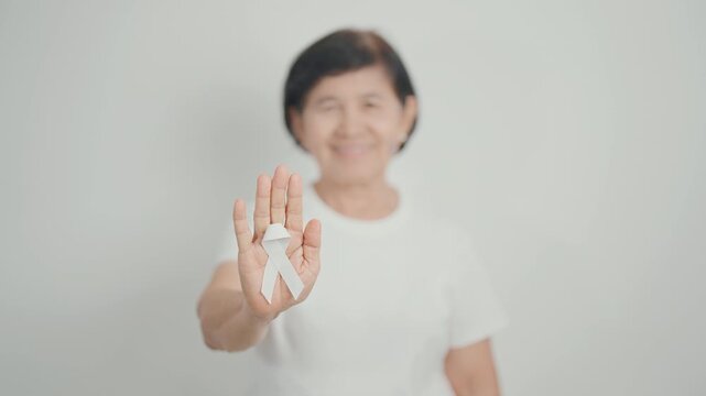 Elderly with White ribbon for concept November Lung Cancer Awareness month, Stop Violence Against Women, Adoption, May Retinoblastoma, Action for Women Health, March Remembrance, October Osteoporosis - Powered by Adobe