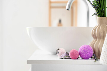 Bath bomb and sea salt on table near sink in interior of bathroom, closeup