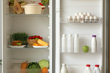 Open big refrigerator with products in kitchen, closeup