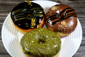 assorted toppings of pistachio, dark and brown chocolates, hazelnut with sauces on ring donuts,...
