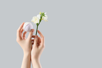 Female hands holding bath bomb and flower on white background