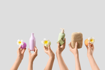 Female hands with bath bombs, soap bar, sponge, flowers and bottles of cosmetic products on white background