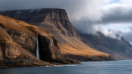 Stunning waterfall cascading down rocky cliffs under a cloudy sky in a scenic coastal landscape
