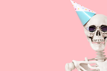 Human skeleton in party hat and sunglasses on pink background, closeup