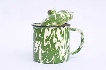 Vintage enamel cup and lid with abstract  green and white pattern isolated on white background with clipping path. Empty White Green tin mug mockup, traditional style. Old-fashioned tin glass.