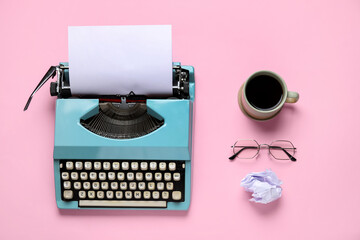 Vintage typewriter with cup of coffee, eyeglasses and crumpled paper on pink background