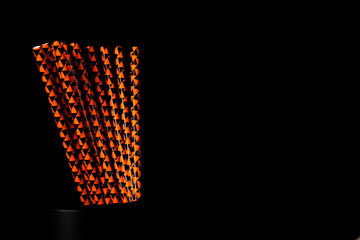 Orange and black paper straws, decorated with a repeating pattern of radiation symbols, stands...