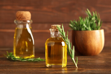 Bottles of rosemary cosmetic oil on wooden background