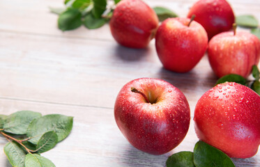Fresh red gala apples with green leaves and water drops on rustic wooden surface