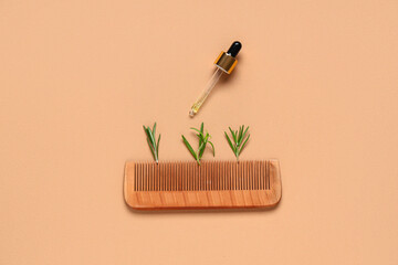 Composition with rosemary leaves, wooden hair comb and pipette on brown background