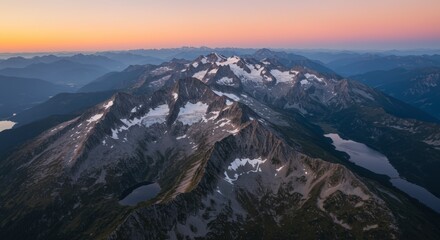 Aerial view of majestic mountain range with snow capped peaks under vibrant sunset sky creating inspiring scenery