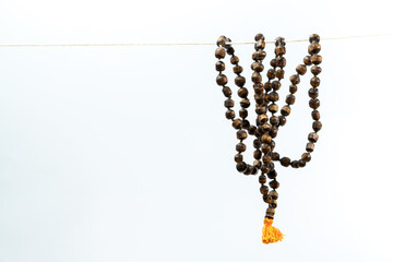 Wooden mala beads hanging against a white background, representing spirituality and mindfulness