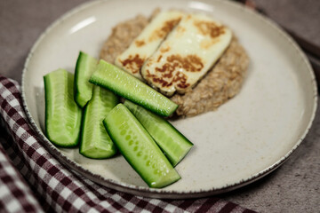 healthy breakfast, porridge oatmeal, fresh green cucumbers, grilled halloumi cheese, simple wellness meal