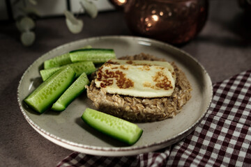 healthy breakfast, porridge oatmeal, fresh green cucumbers, grilled halloumi cheese, simple wellness meal
