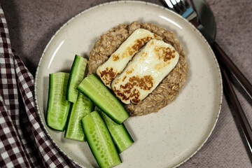 healthy breakfast, porridge oatmeal, fresh green cucumbers, grilled halloumi cheese, simple wellness meal