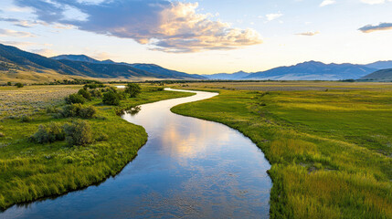 Obraz premium Serene river flows through lush green landscape, surrounded by mountains and colorful sky sunset. tranquil scene evokes sense of peace and natural