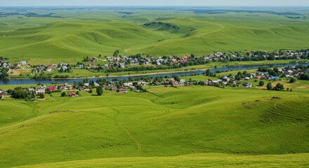 Expansive green landscape with rolling hills and a river bisecting a small settlement under a clear sky