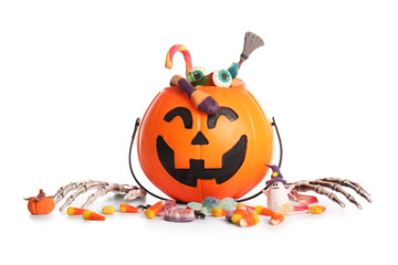 Cauldron in shape of pumpkin with candies for Halloween and skeleton hands isolated on white background