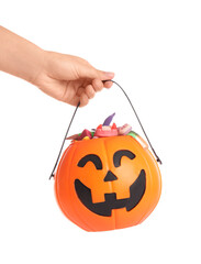 Female hand holding cauldron in shape of pumpkin with candies for Halloween isolated on white background