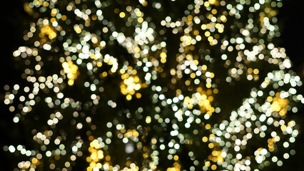 Defocused string lights on christmas tree, shiny gold yellow blurred bokeh circle background wallpaper for festive season celebration. 