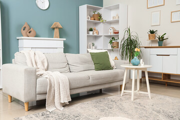 Interior of stylish living room with grey sofa, table and shelf unit