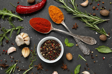 Composition with herbs and spices on black grunge background, closeup