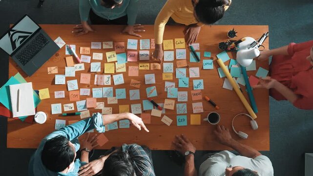 Top view of smart business team explain and discuss about project design at meeting room with laptop and sticky notes. Aerial view of designer designing logo brand design while standing. Symposium.