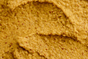 Mustard sauce with grains close-up. Hot spices as a background. Texture of Dijon mustard.