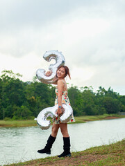 A happy Asian woman takes a photo of her 33rd birthday, smiling brightly. Location: Lam Takhong, Khao Yai, Nakhon Nayok Province, Thailand.