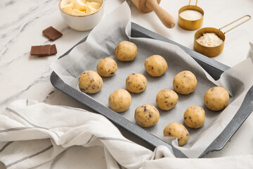Composition with baking tray, raw cookies and ingredients on marble background, closeup